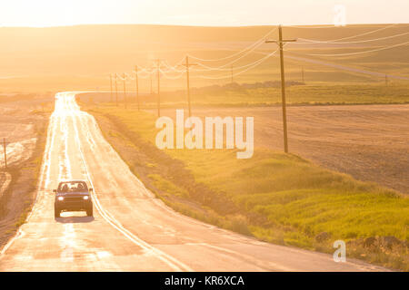 Auto auf langen geraden Autobahn öffnen bei Sonnenuntergang unterwegs. Stockfoto