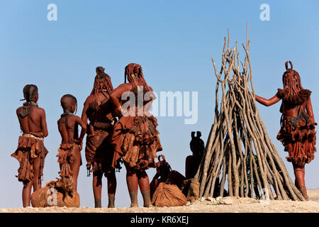 Kleine Gruppe von Himba Frauen und Kinder tragen traditionelle Kleidung in einer Wüste. Stockfoto