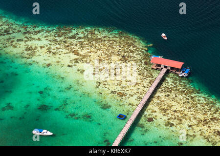 Hohe Betrachtungswinkel der tropischen Insel, lange Seebrücke und Strand Haus, Boote im Meer vor Anker. Stockfoto