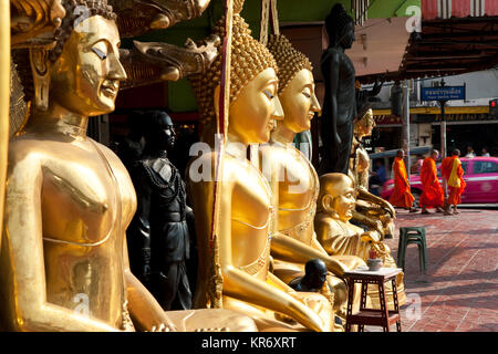 Hohe goldene Buddha Statuen aufgereiht auf einem Gehsteig. Stockfoto