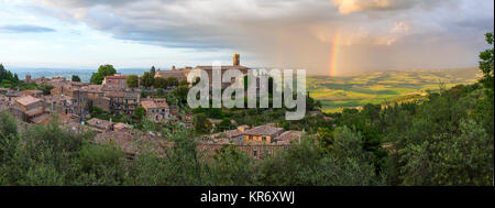 Landschaft mit kleinen Stadt mit historischen Häusern, umgeben von Bäumen, Regenbogen in der Ferne. Stockfoto