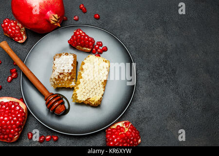 Granatapfel und Wabe close-up auf dunklen konkreten Hintergrund Stockfoto