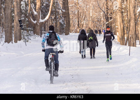 Montreal, CA - 17. Dezember 2017: Die Menschen laufen und Fahrrad fahren auf Schnee in den Mont Royal Park Stockfoto