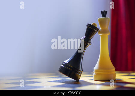 Schach schwarze Königin und weiße König stand auf einem Holz- Schachbrett. Die schwarze Königin legte ihren Kopf auf die Brust zu den weissen König. Stockfoto