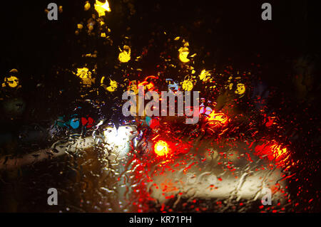 Regentropfen auf dem Fenster. City lights verwischt durch Wasser fällt auf Glas. Stockfoto