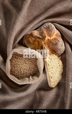 Brot und ein Beutel der Körner auf einem Sack Stockfoto