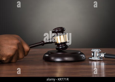 Nahaufnahme eines Richters Hände markante Hammer am Schreibtisch Stockfoto
