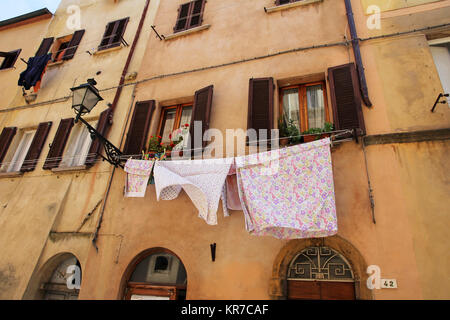 Eine Wäscheleine mit Wäsche der Ein altes Haus in Italien. frisch gewaschene Kleidung vor einem Haus Stockfoto