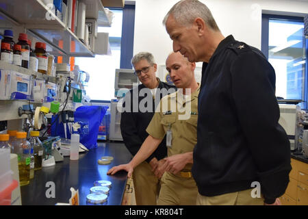 Lt.Cmdr. Mark Simons (Mitte), der medizinische Forschung (NMRC), Infektionskrankheiten, Direktion, zeigt hinten Adm. Paul Pearigen, Commander, Marine Medizin West, Chef der Marine Medical Corps (vorne) und Kapitän Adam Armstrong (hinter), kommandierender Offizier, NMRC, ein Labor Wundinfektion Modell bei einem Besuch in NMRC, November 27. Stockfoto