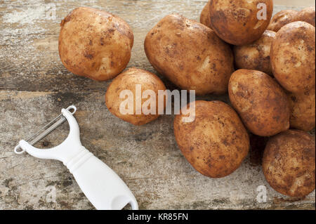 Kunststoff und Metall Schäler mit rohen Kartoffeln Stockfoto