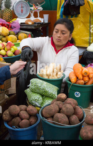 Cuenca Ecuador - einem standbesitzer in der Lebensmittel Gemüse Verkauf von ihrem Marktstand, Markthalle Cuenca, Cuenca, Ecuador Südamerika Stockfoto