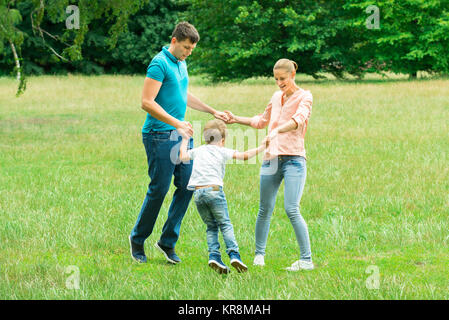 Glückliche junge Familie halten sich an den Händen Stockfoto