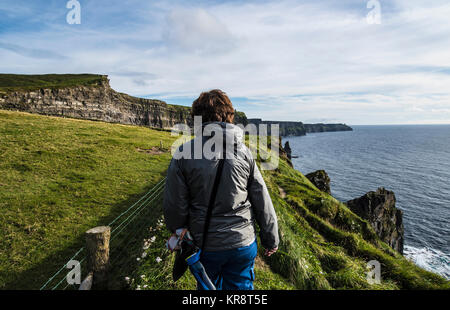 Irland, County Clare, Frau entlang den Klippen von Moher Stockfoto