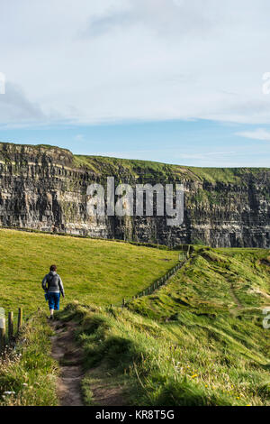 Irland, Clare County, Frau entlang den Klippen von Moher Stockfoto