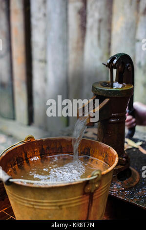 Das Wasser aus dem Eimer gießen in der Pumpe Stockfoto