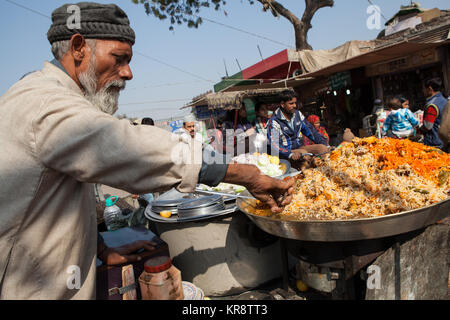 Ein muslimischer Mann bereitet eine Portion chicken Biryani in der Altstadt von Delhi, Indien Stockfoto