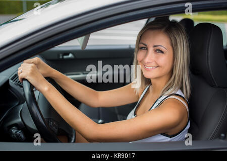 Frau Auto fahren - weibliche Fahrer an einem Rad eines modernen Autos, glücklich lächelnd mit einem entspannten Lächeln (flacher DOF Farbe getonte Bild) Stockfoto