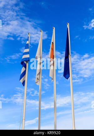 Zypern, Griechenland, der EU und der Gemeinde Larnaka Fahnen Fahnenmasten. Bewölkter Himmel Hintergrund. Stockfoto