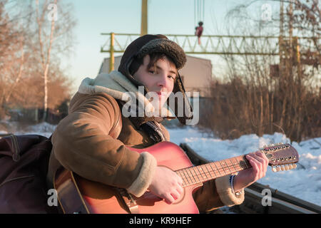 Kerl auf Schienen im Winter Gitarre Spielen Stockfoto