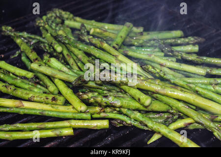 Ein Haufen von Gebutterte Spargelspitzen Braten auf einen Grill im Freien mit Rauch aus Ihnen Stockfoto
