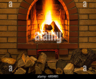 Stapel von Holz und Zungen aus Feuer in indoor gemauerten Kamin im
