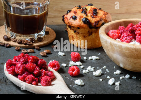 Quark mit Himbeeren, Kaffee in eine Tasse und Blueberry Muffin zum Frühstück Stockfoto