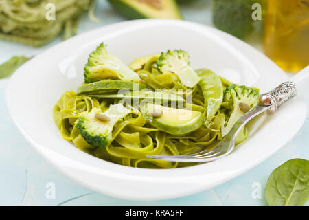 Gesunder Spinat Nudeln mit Brokkoli, Avocado, Kürbiskerne und grünen Erbsen. Vegane Ernährung Essen Konzept. Stockfoto