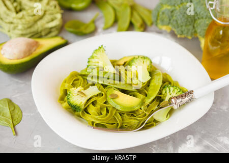 Gesunder Spinat Nudeln mit Brokkoli, Avocado, Kürbiskerne und grünen Erbsen. Vegane Ernährung Essen Konzept. Stockfoto