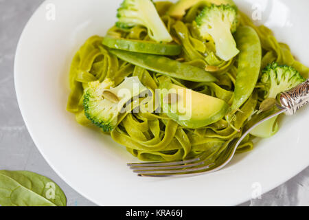 Gesunder Spinat Nudeln mit Brokkoli, Avocado, Kürbiskerne und grünen Erbsen. Vegane Ernährung Essen Konzept. Stockfoto