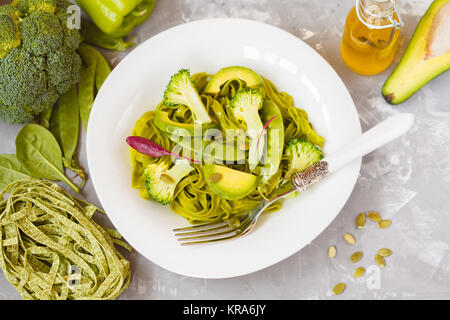 Gesunder Spinat Nudeln mit Brokkoli, Avocado, Kürbiskerne und grünen Erbsen. Ansicht von oben. Vegane Ernährung Essen Konzept. Stockfoto