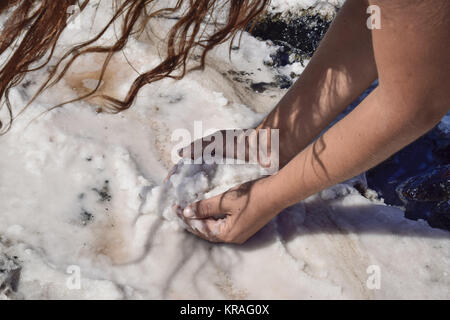 Hände Mädchen, die auf der nassen Salz aus den Pfützen Stockfoto