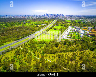 Luftaufnahme von einer grünen Parklandschaft, Melbourne Polytechnikum, und Melbourne CBD Wolkenkratzer im Abstand im Sommer Tag Stockfoto