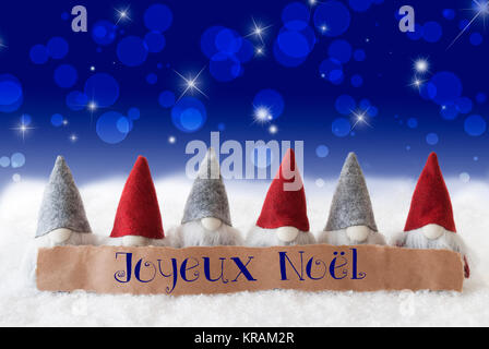 Etikett mit französischen Text Joyeux Noel bedeutet, frohe Weihnachten. Weihnachten Grußkarten mit Gnome. Sekt Bokeh und Blauer Hintergrund mit Schnee und Sterne. Stockfoto