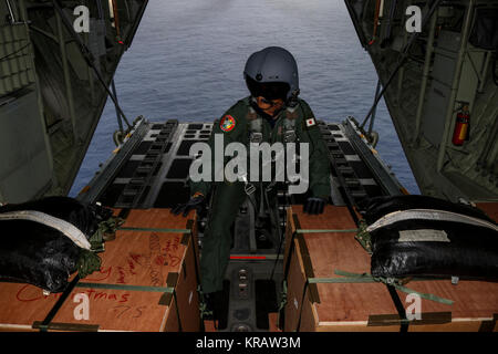 Master Sgt. Noriaki Nakaoka, 1 Tactical Air Wing 401st Squadron Lademeister, hält an zu zwei Bündeln, bevor Sie sie aus einem Koku Jieitai (Japan Air Self Defense Force) C-130H Hercules während der 66th Betrieb Weihnachten Drop, Dez. 13, 2017. Das Bordpersonal hat vier Bündel zu zwei verschiedenen Mikronesischen Inseln während dieser Ausbildung sortie. (U.S. Air Force Stockfoto