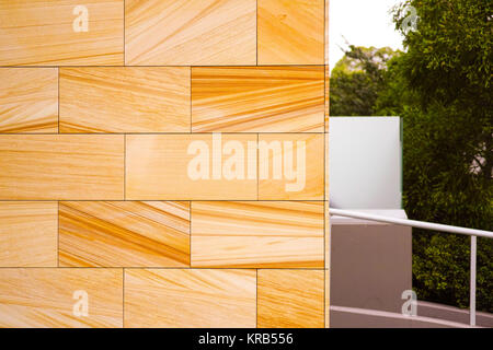 Die modernen architektonischen Sandstein Block Gebäude Exterieur. Orange Haus aus Stein an der Wand neben dem grünen Bäumen. Architektur Detail in Rhodos, Sydney, Australien. Stockfoto