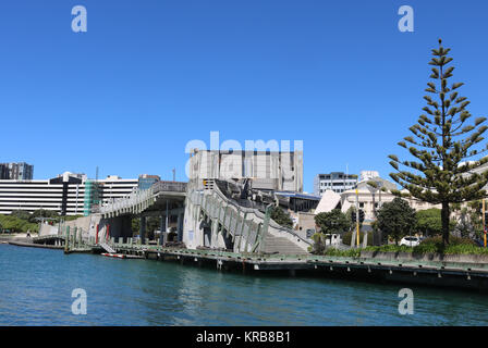 Blick über die Stadt zum Meer Brücke auf der Uferpromenade in Wellington, Neuseeland, die einige der aus Holz geschnitzte Skulpturen von paratene Matchitt. Stockfoto