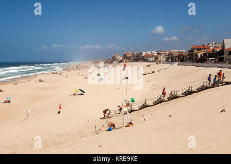 Badende am Strand von Marinha Grande, Portugal. Holz- Stufen führen hinunter auf den Sandstrand. Stockfoto