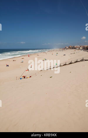 Badende am Strand von Marinha Grande, Portugal. Holz- Stufen führen hinunter auf den Sandstrand. Stockfoto