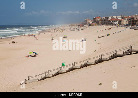 Badende am Strand von Marinha Grande, Portugal. Holz- Stufen führen hinunter auf den Sandstrand. Stockfoto