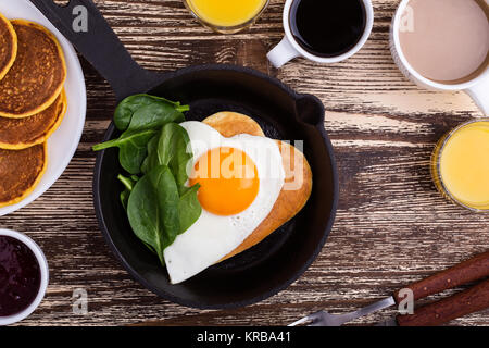 Valentinstag Frühstück oder Brunch. Hausgemachte Herzform Spiegelei und Pfannkuchen in Gusseisen Skillet mit Spinat, Orangensaft und Kaffee. T Stockfoto