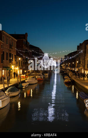 Weihnachtsbeleuchtung im Canal vetrai an der blauen Stunde, Murano Venedig, Italien mit funkelnden Lichtreflexe und Fußgänger auf der Fondamenta dei Vetrai Stockfoto