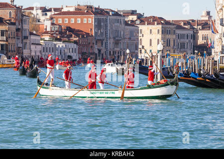 Feiern Weihnachten in Venedig, Italien während der babbo Natale regatta Parade, Grand Canal mit Menschen in rot Santa Kostüme Ruderboote Stockfoto