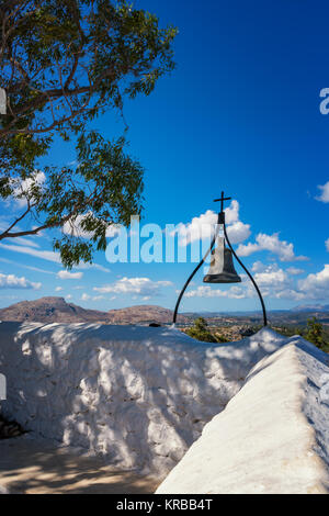 Bronzene Glocke mit Kreuz an der Wand von Tsambika Kloster (Rhodos, Griechenland) Stockfoto