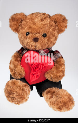 Eine niedliche Teddybär hält ein rotes Herz geformt, auf weißem Hintergrund Stockfoto