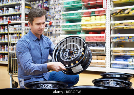 Mann wählt und kauft mit Rädern metal Platten für ein Auto in einem Laden. Stockfoto