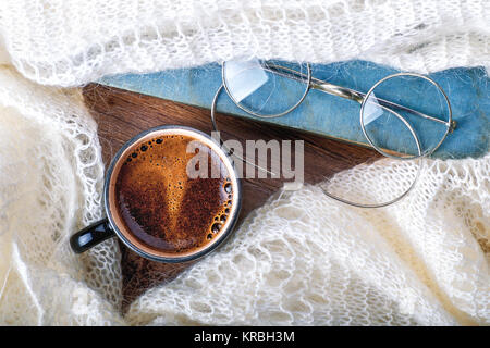 Eine Tasse Kaffee, Schal, Pullover oder warmem Plaid gewickelt, mit einem Buch und Brille. Herbst oder Winter, Wochenende, Feiertag oder Guten Morgen Konzept. Clos Stockfoto