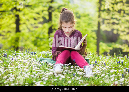 Kleines Mädchen Lesung buchen Sie im Park Stockfoto