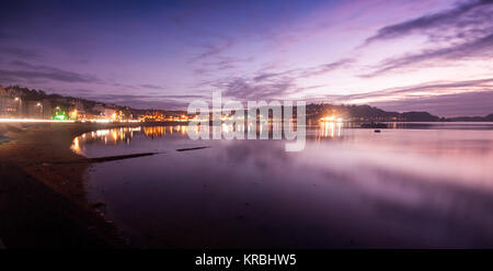 Die Lichter der Stadt Oban sind im Meer Wasser entlang der Schleife der Oban Bay bei Sonnenuntergang in der Argyll Bezirk der West Highlands von Schottland wider. Stockfoto