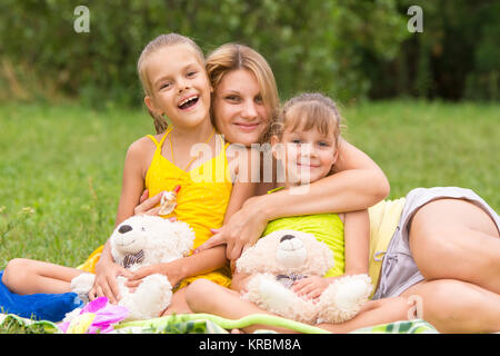 Junge Mutter auf ein Picknick umarmt, zwei Töchter, fünf und sieben Jahren Stockfoto