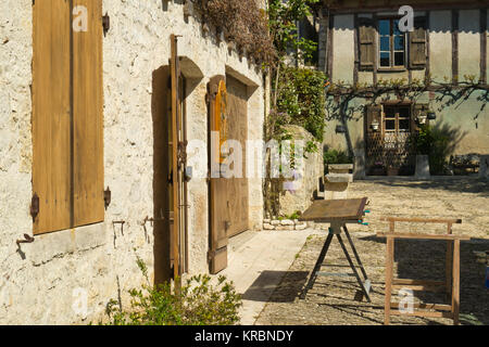 Traditionelle hölzerne Fensterläden, repariert und neu lackiert warten auf eine Werkbank außerhalb einer idyllischen alten Cottage in Pujols, Lot-et-Garonne, Frankreich Stockfoto